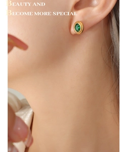 Gros plan de boucles d'oreilles dorées avec zircon vert ovale au style hip-hop
