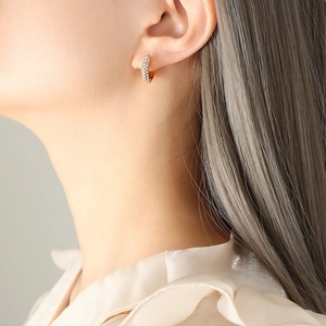Elegant gold hoop earrings with pavé white zircons shown on model in close-up shot
