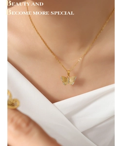Détail d'un collier papillon doré serti de zircons sur le cou d'une femme élégante