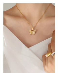 Détail du pendentif papillon doré avec zircons et texture sur le cou d'un mannequin élégant