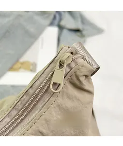 Dettaglio della cerniera frontale su una borsa a tracolla in nylon con cuciture precise