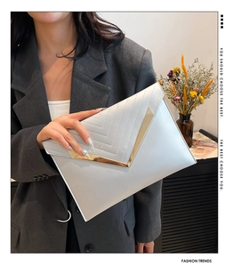 Detail of elegant envelope clutch bag with V-shaped gold metal trim and stitching