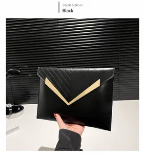 Detail of black envelope clutch featuring V-shaped gold metal trim and quilted stitching