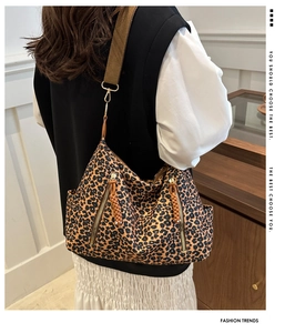 Detail view of leopard print tote bag with brown woven straps and front zipper pockets