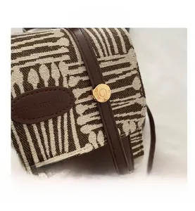 Detailed macro view of woven plaid fabric with leather trim and golden metal clasp