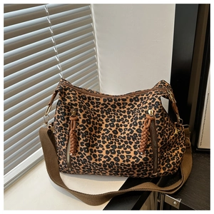 Detailed view of leopard print shoulder bag with brown woven tassels and zip pockets