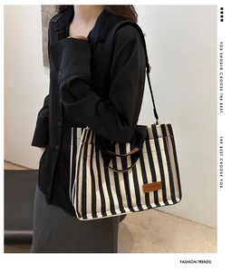 Detail of striped canvas tote bag showing the fashion label and sturdy fabric strap