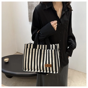 Detail of black and white striped canvas tote with brown leather FASHION patch