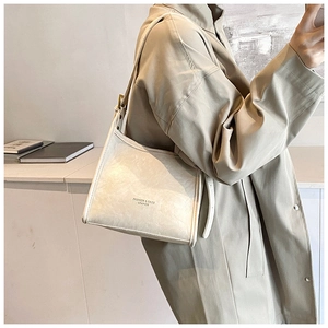 Detail of minimalist cream leather tote bag with embossed text and adjustable wide strap