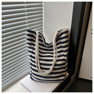 Detail of nautical navy striped canvas tote bag with thick rope handles on a book