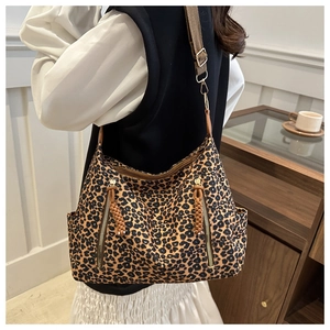 Detail of leopard print tote bag with brown woven zipper pulls and wide shoulder strap