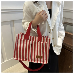 Detailed view of striped canvas tote bag with front pockets and brown leather label