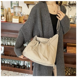 Dettaglio borsa a tracolla in tela beige con tasca frontale a coulisse in stile casual