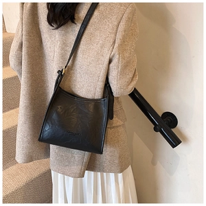 Detail of a minimalist black vintage trapezoid shoulder bag in a grainy PU leather finish