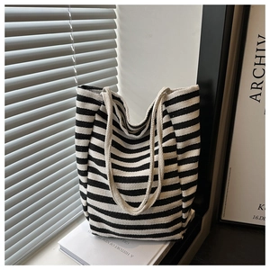 Classic black and white striped canvas tote bag detail on books with woven strap