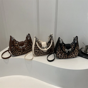 Three leopard print crescent crossbody bags with metal bow buckle on white steps
