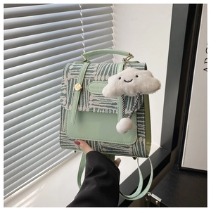 Detail of mint green plaid fabric texture and white cloud plush charm on backpack