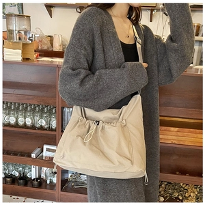 Dettaglio della borsa beige in nylon con grande tasca a coulisse e ampia tracolla regolabile