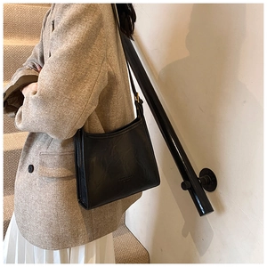 Detail of minimalist black tote bag with smooth leather texture and adjustable strap