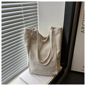 Detail of herringbone weave texture on beige corduroy tote bag with soft natural light