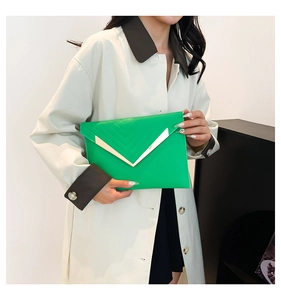 Detail of neon green envelope clutch bag featuring gold V-shaped metal hardware detail
