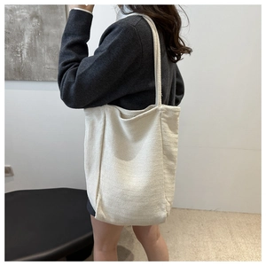Détail du sac cabas en toile beige montrant la texture à chevrons et le tissu résistant