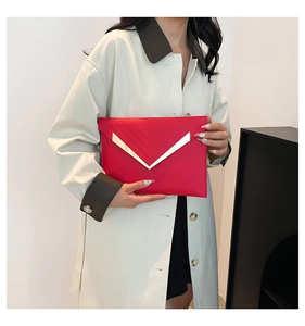 Detail of red envelope clutch featuring gold V-shaped metal trim and quilted pattern