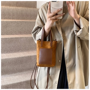 Detail of camel brown faux suede mini crossbody bag with smooth leather patch pocket