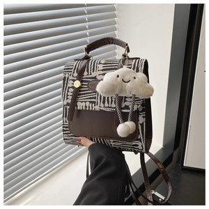Detail of plaid patterned crossbody bag with plush cloud charm and leather texture