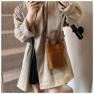 Detail of a brown suede crossbody phone bag with rectangle leather pocket and knotted strap