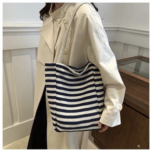 Detail view of large striped canvas tote bag with thick rope shoulder strap worn by a model