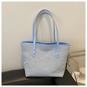 Close-up of light blue tote bag featuring textured crinkle fabric and gold rivet details