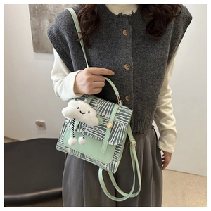 Detail of mint green crossbody bag with geometric pattern flap and white cloud charm