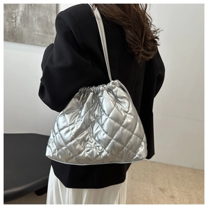 Quilted silver tote bag with drawstring closure and bow detail shown on a model