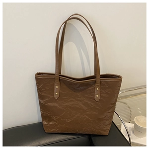 Macro detail of dark brown tote bag with wrinkled paper texture and gold rivets