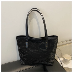 Close-up of black tote bag featuring unique crinkle texture and gold rivet hardware