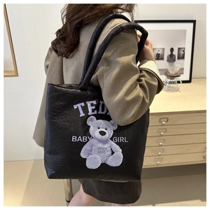 Quilted black puffer tote bag with teddy bear print shown in a lifestyle setting