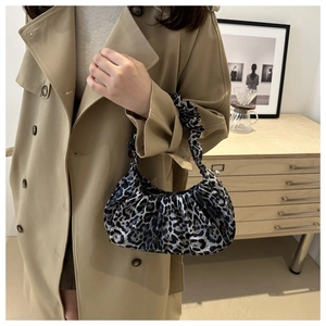Detail of leopard print pleated handbag styled with a camel trench coat in a cozy setting