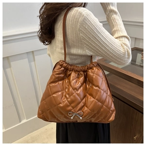Close-up of caramel brown quilted tote bag with silver bow detail and drawstring closure