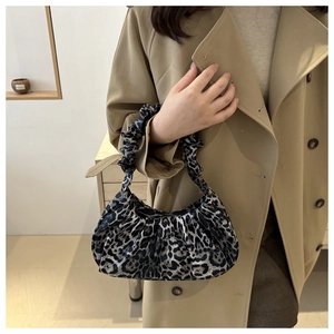 Close-up of leopard print pleated shoulder bag with soft velvet texture on beige coat