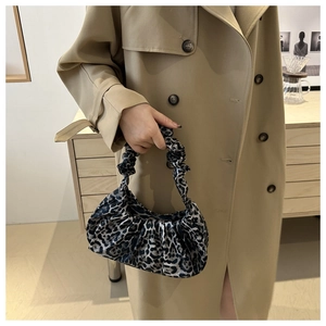 Detail of leopard print pleated shoulder bag paired with an elegant khaki trench coat