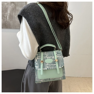 Detail of mint green leather and woven tote bag worn by model in casual interior