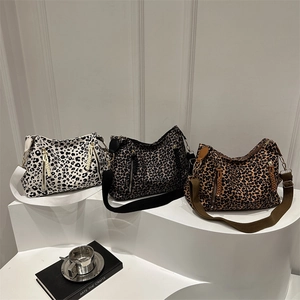 Three leopard print canvas crossbody bags in black, grey, and brown on white pedestals