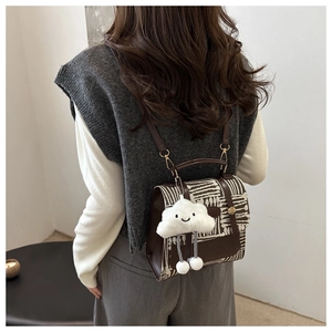 Detail of British style casual backpack in brown leather and textured fabric with cloud charm