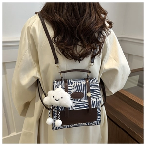 Detail view of vintage plaid small backpack with cute cloud plush charm and brown leather straps