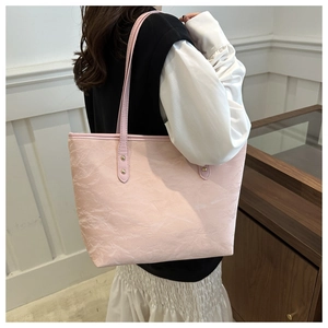 Detail of pink tote bag showing unique crinkled texture and metallic rivet accents