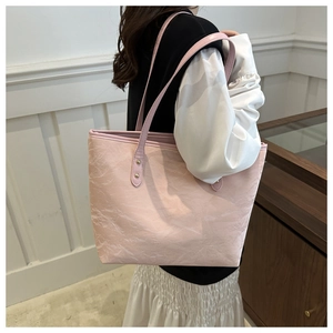Side view of pink pleated texture tote bag with shoulder strap and gold rivets