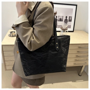 Detailed view of black wrinkled texture tote bag styled with a professional blazer