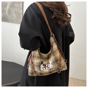 Close-up of checkered fabric shoulder bag featuring a cute cartoon dog print and leather strap