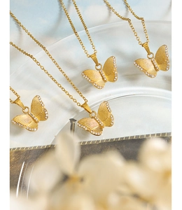 Détail du pendentif papillon doré avec incrustation de zircon et ailes texturées